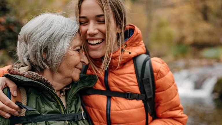 Nuorempi ja iäkkäämpi nainen halaavat retkipolulla.